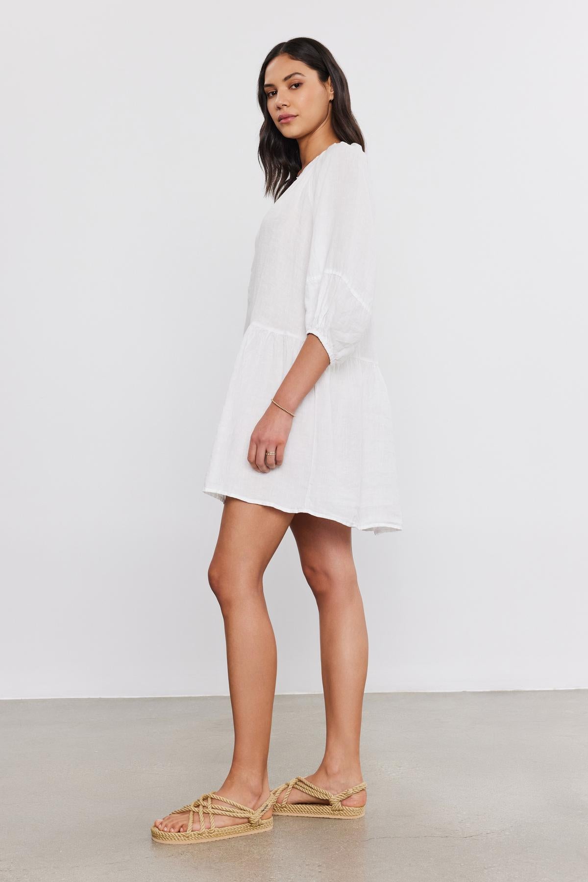   A woman in a VONNIE LINEN DRESS by Velvet by Graham & Spencer and espadrille shoes stands in a profile pose against a grey background. 