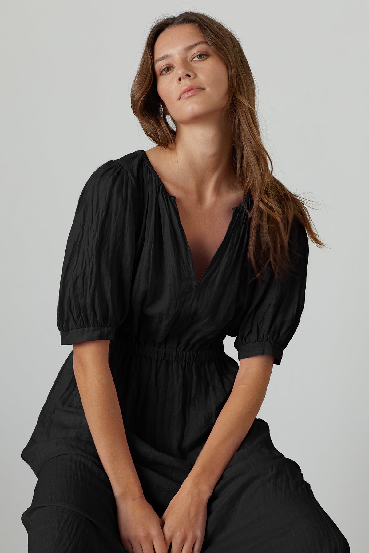 The model is wearing a black Velvet by Graham & Spencer WHITNEY LINEN CUT OUT DRESS.-26671394357441