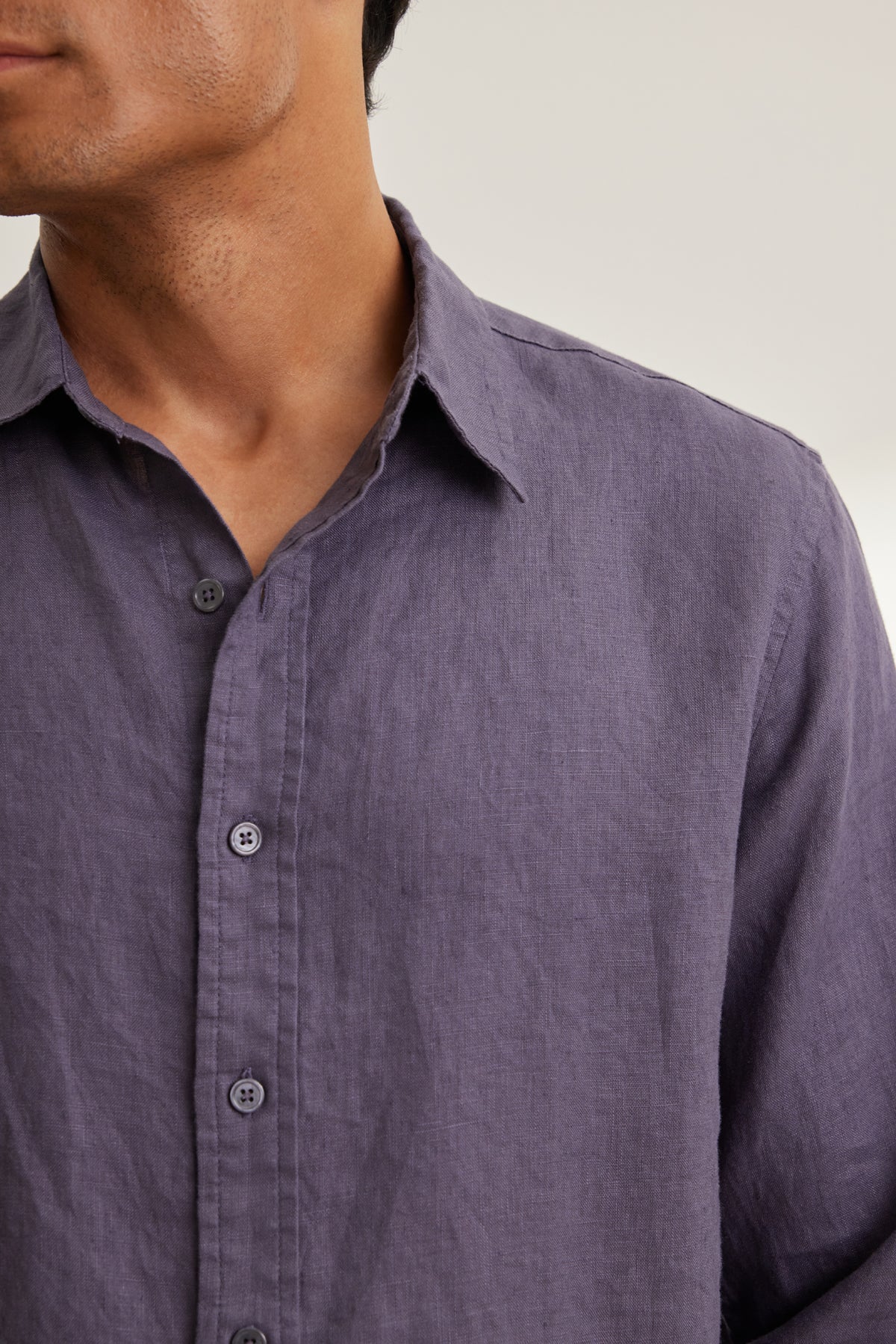   A person models the CARUSO LINEN BUTTON-UP SHIRT by Velvet by Graham & Spencer, a classic long-sleeve purple linen shirt, set against a neutral background. 