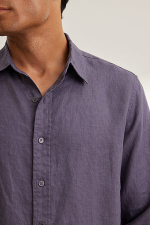 A person models the CARUSO LINEN BUTTON-UP SHIRT by Velvet by Graham & Spencer, a classic long-sleeve purple linen shirt, set against a neutral background.