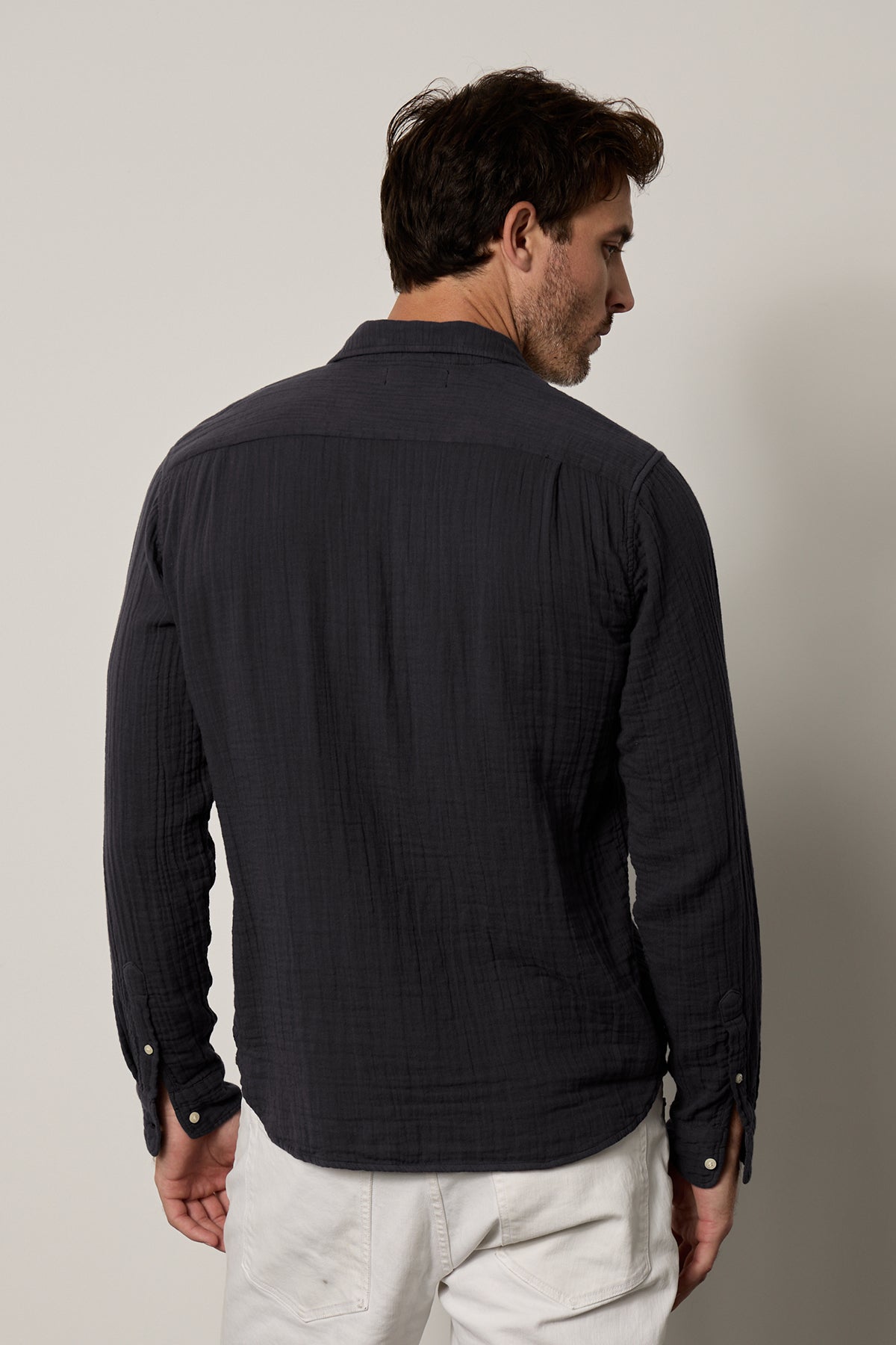the back view of a man wearing the Velvet by Graham & Spencer ELTON BUTTON-UP SHIRT and white pants.-35206158418113