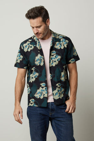 A man wearing an IGGY PRINTED BUTTON-UP SHIRT by Velvet by Graham & Spencer and jeans for his summer vacations.