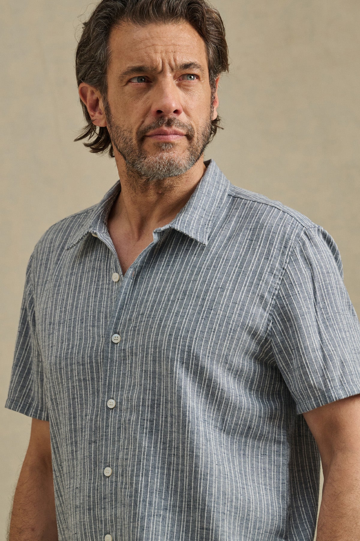 A man wears the KAIDEN SHIRT by Velvet by Graham & Spencer, a short-sleeve cotton shirt with a classic collar and white vertical stripes, standing against a neutral background.-41548219482305