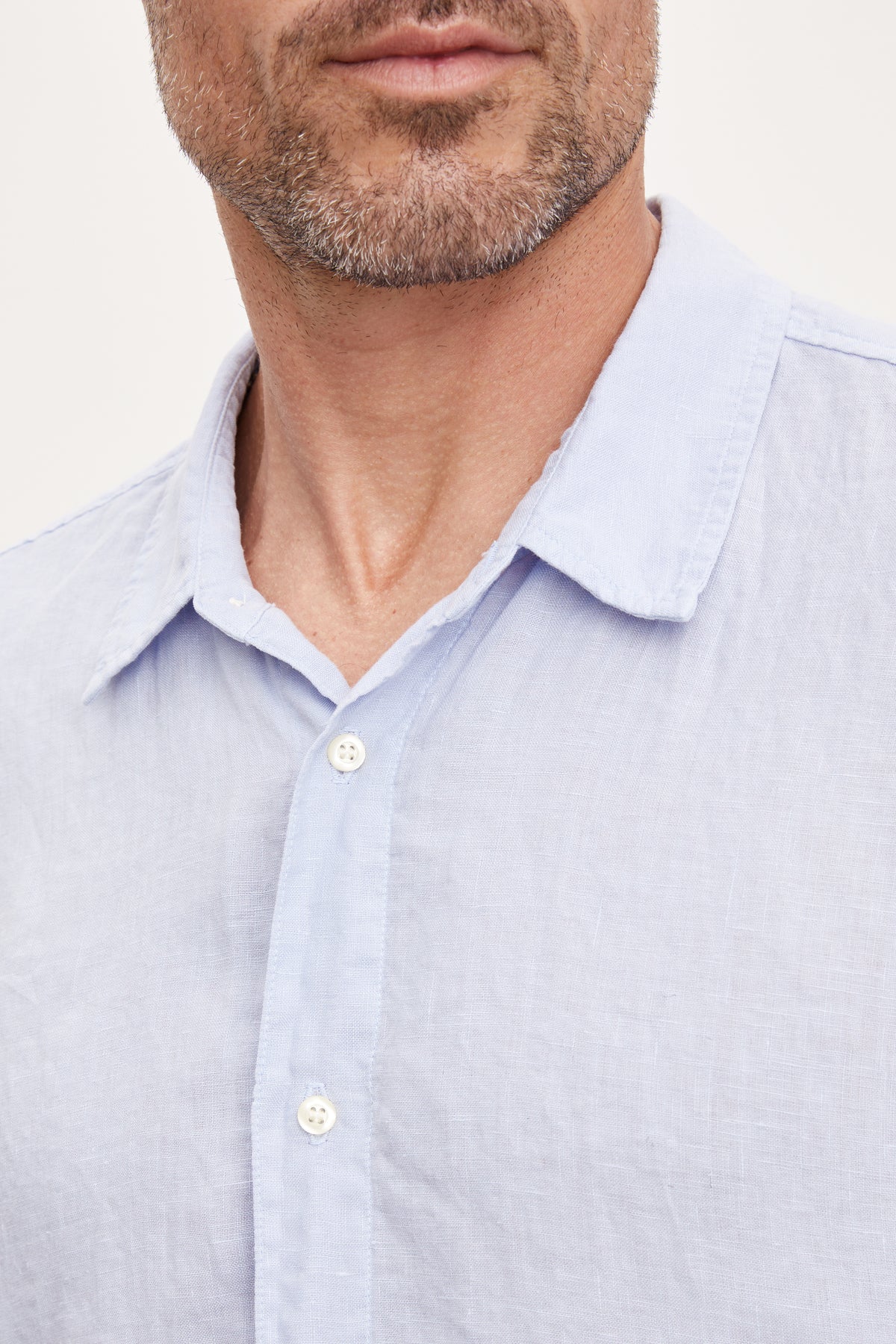   Close-up of a man wearing a Velvet by Graham & Spencer MACKIE LINEN BUTTON-UP SHIRT, focusing on the collar and top buttons. 