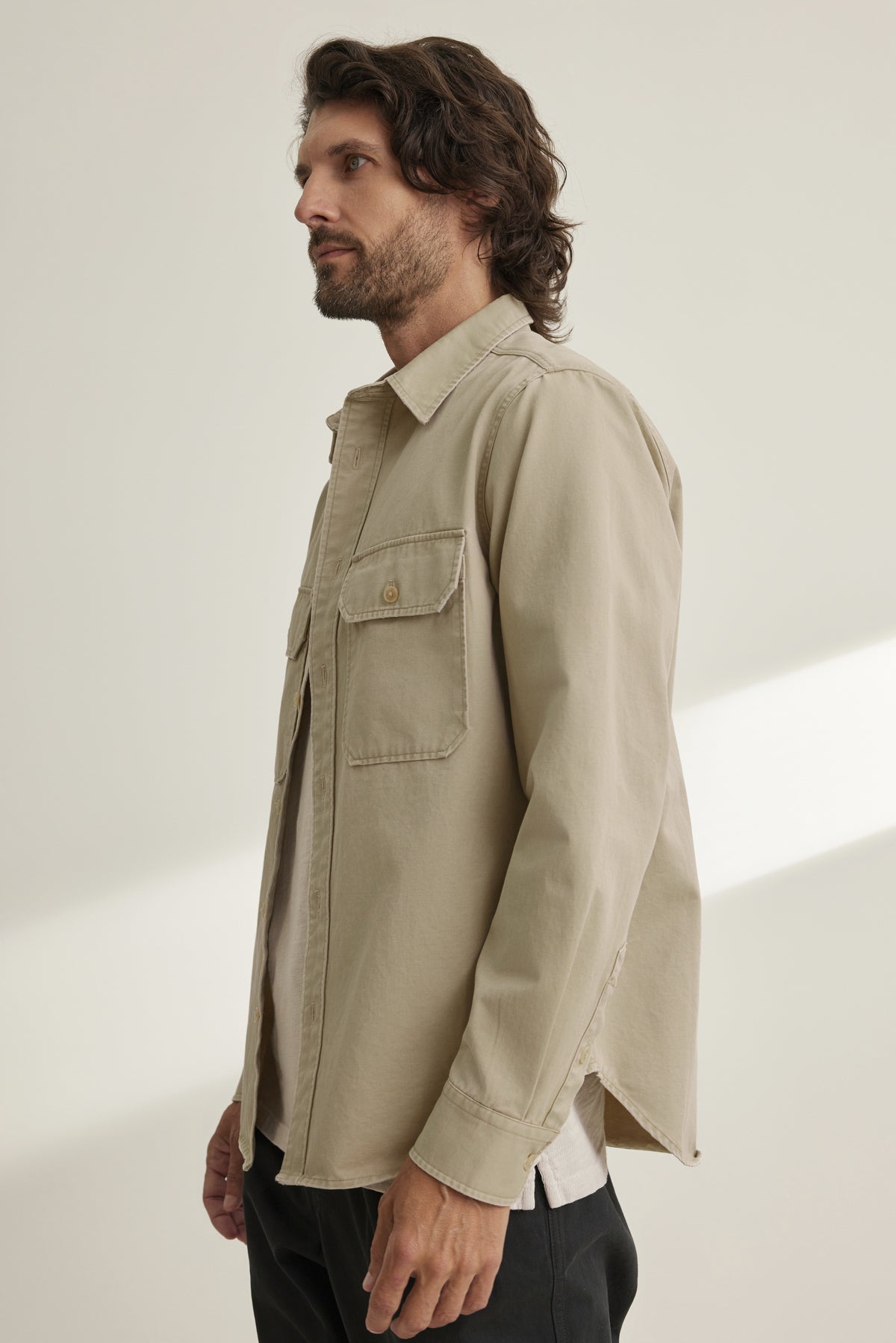 A man in profile wears the ORLANDO BUTTON-UP SHIRT by Velvet by Graham & Spencer, featuring chest pockets, paired with dark pants against a light background.-38643339886785