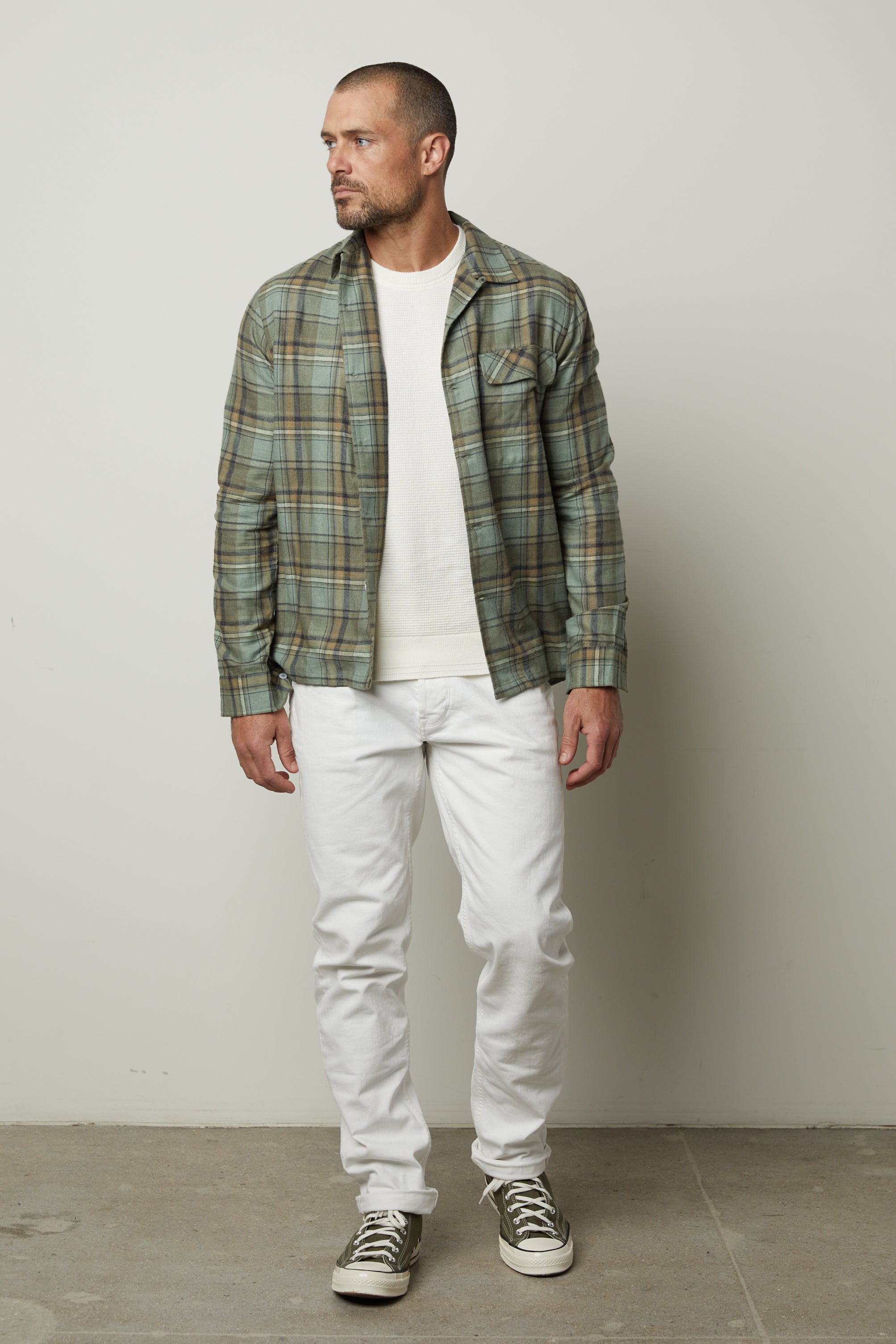   A man wearing white jeans and a Velvet by Graham & Spencer TIMOTHY PLAID BUTTON-UP SHIRT. 