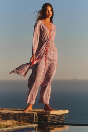 A woman stands barefoot by a pool, framed by ocean and sky, wearing the WRENLEY DRESS from Velvet by Graham & Spencer—a cotton voile midi dress with embroidered detailing.