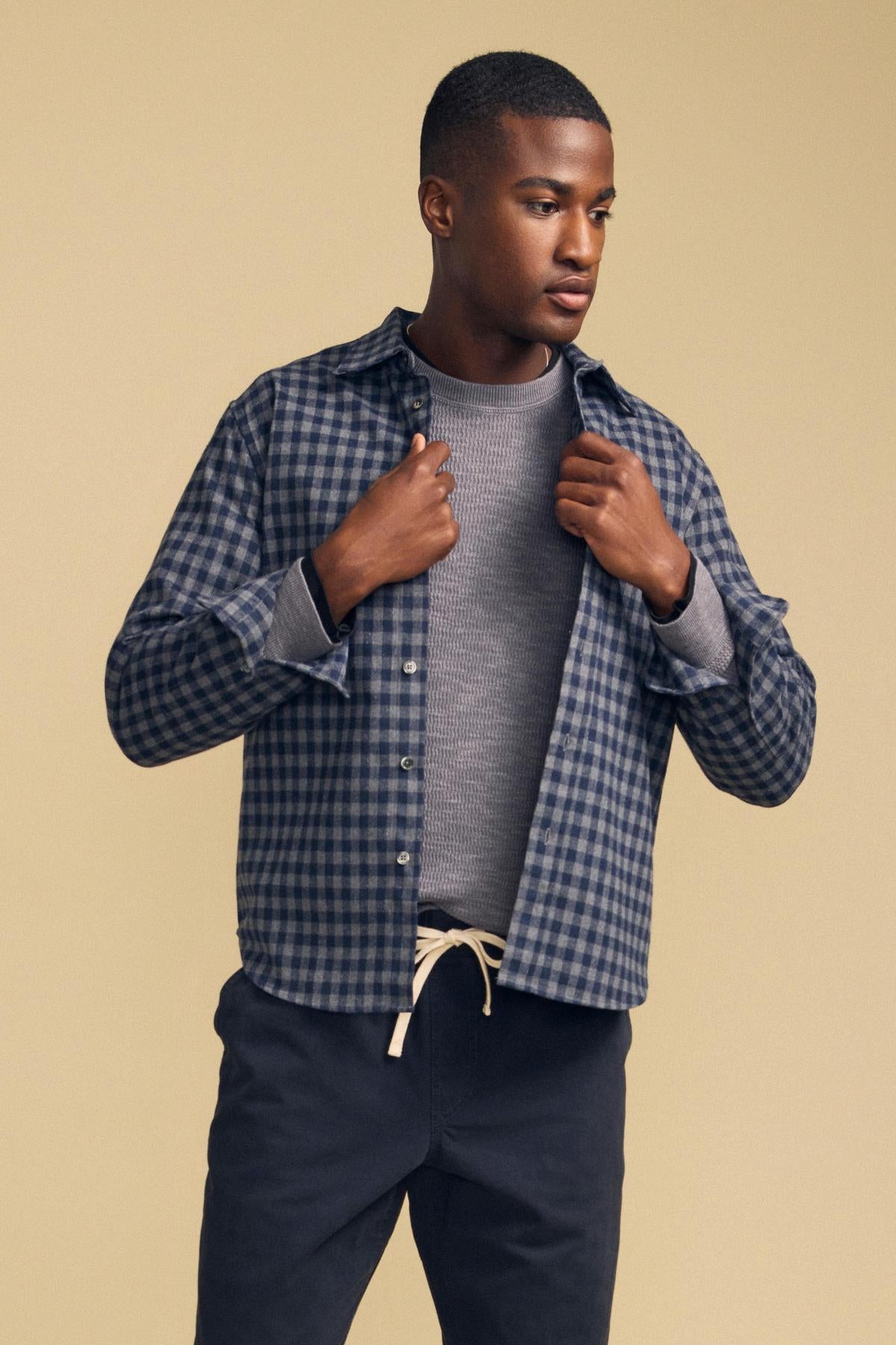 A man wearing a blue and grey DANNY PLAID BUTTON-UP SHIRT over a grey crewneck sweater.-46287908339905