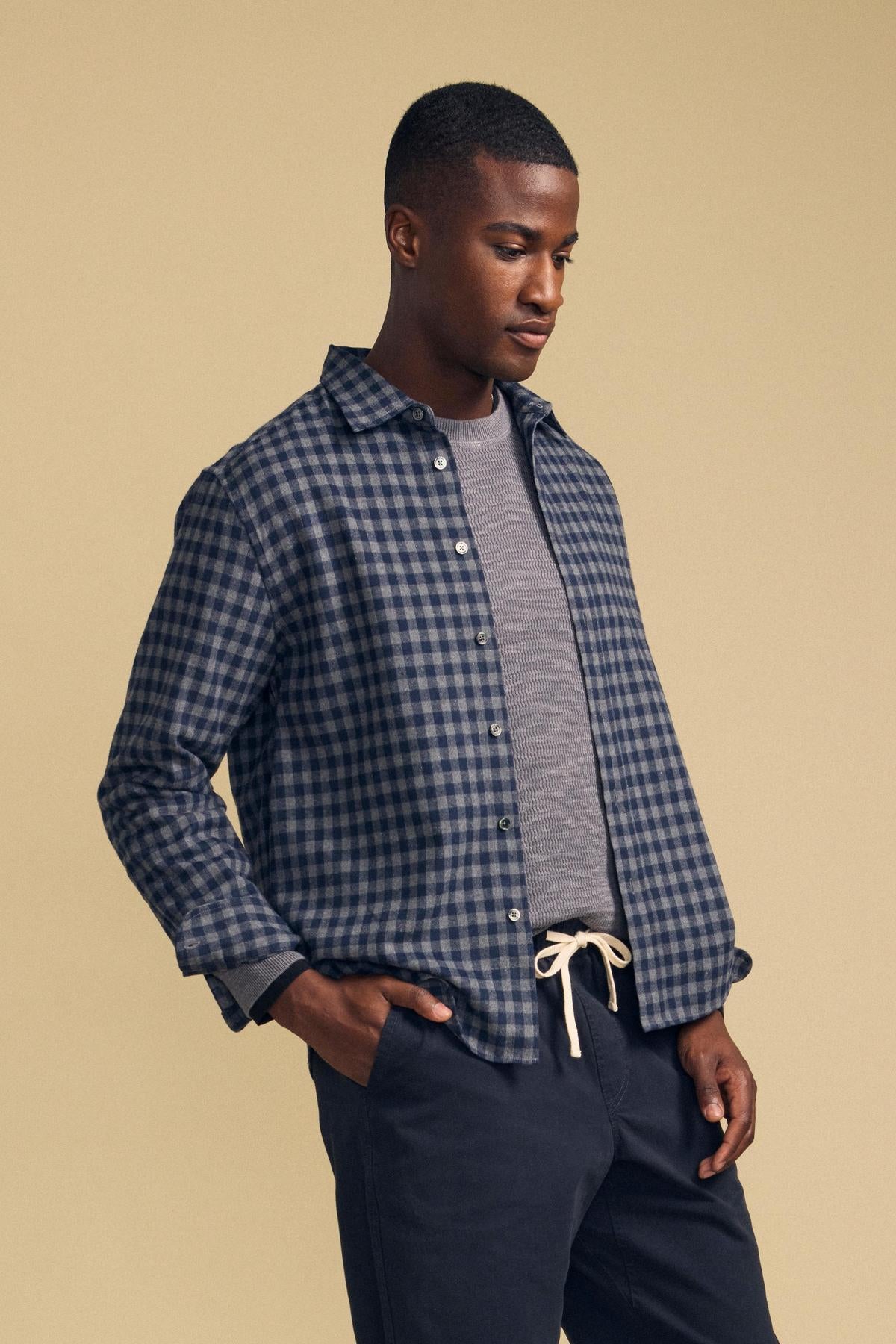 A person wears an unbuttoned blue and gray plaid DANNY PLAID BUTTON-UP SHIRT by Velvet by Graham & Spencer over a gray shirt and dark pants.-46287908405441