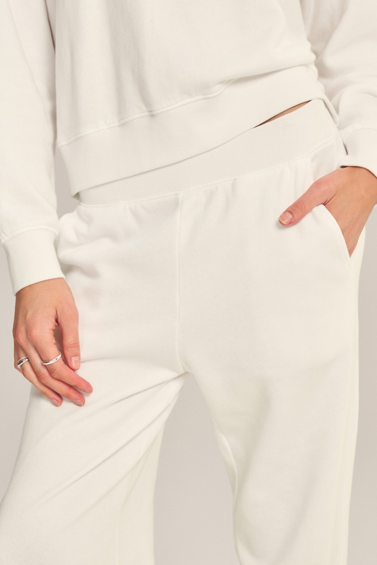 Person wearing a white sweatshirt and ZARA SWEATPANT by Velvet by Graham & Spencer in cotton fleece, featuring a relaxed fit with one hand in a pocket and the other resting at their side.