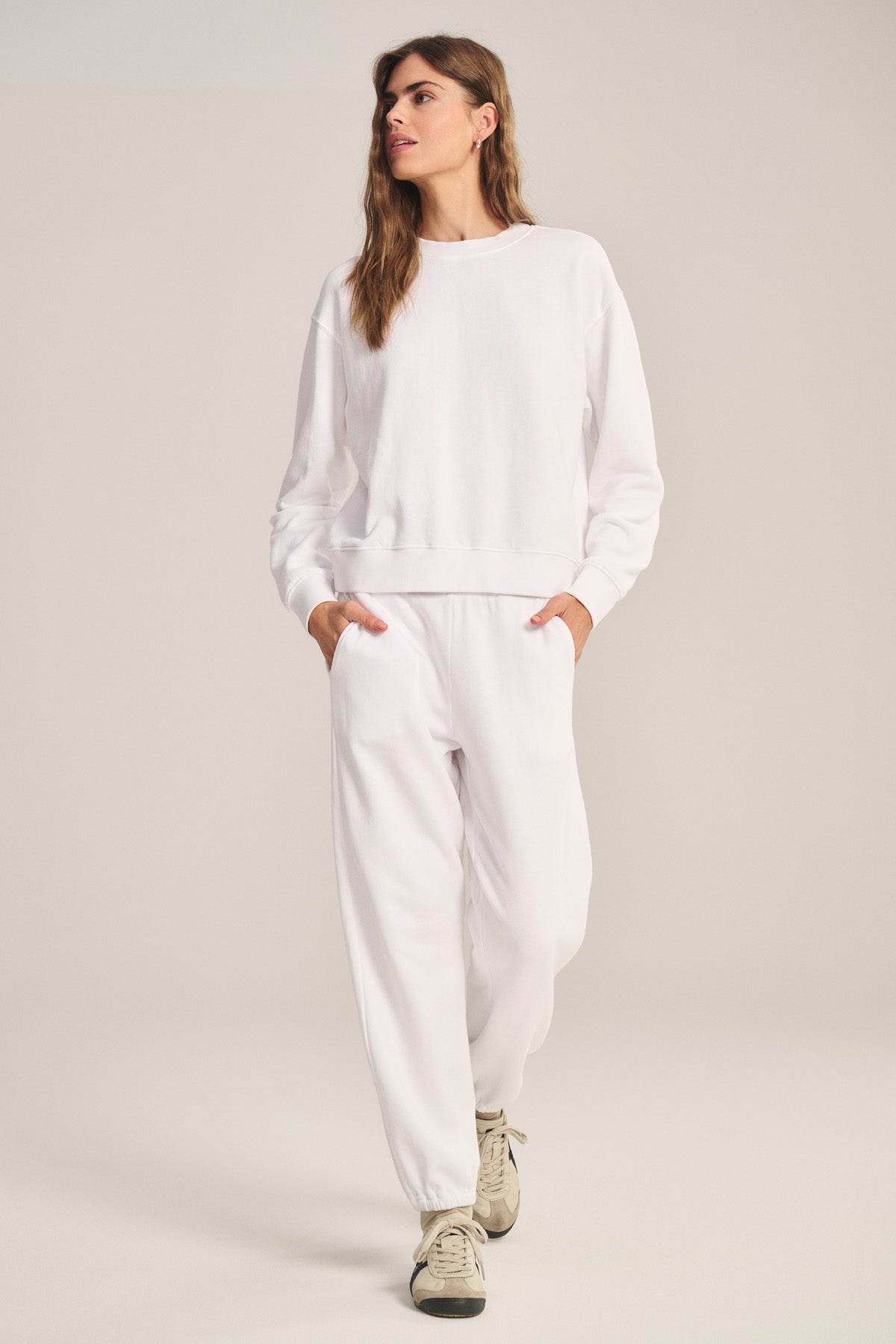A person stands with hands in pockets, wearing the YOKO SWEATSHIRT by Velvet by Graham & Spencer and matching sweatpants, paired with white sneakers, against a plain background.-40293969232065