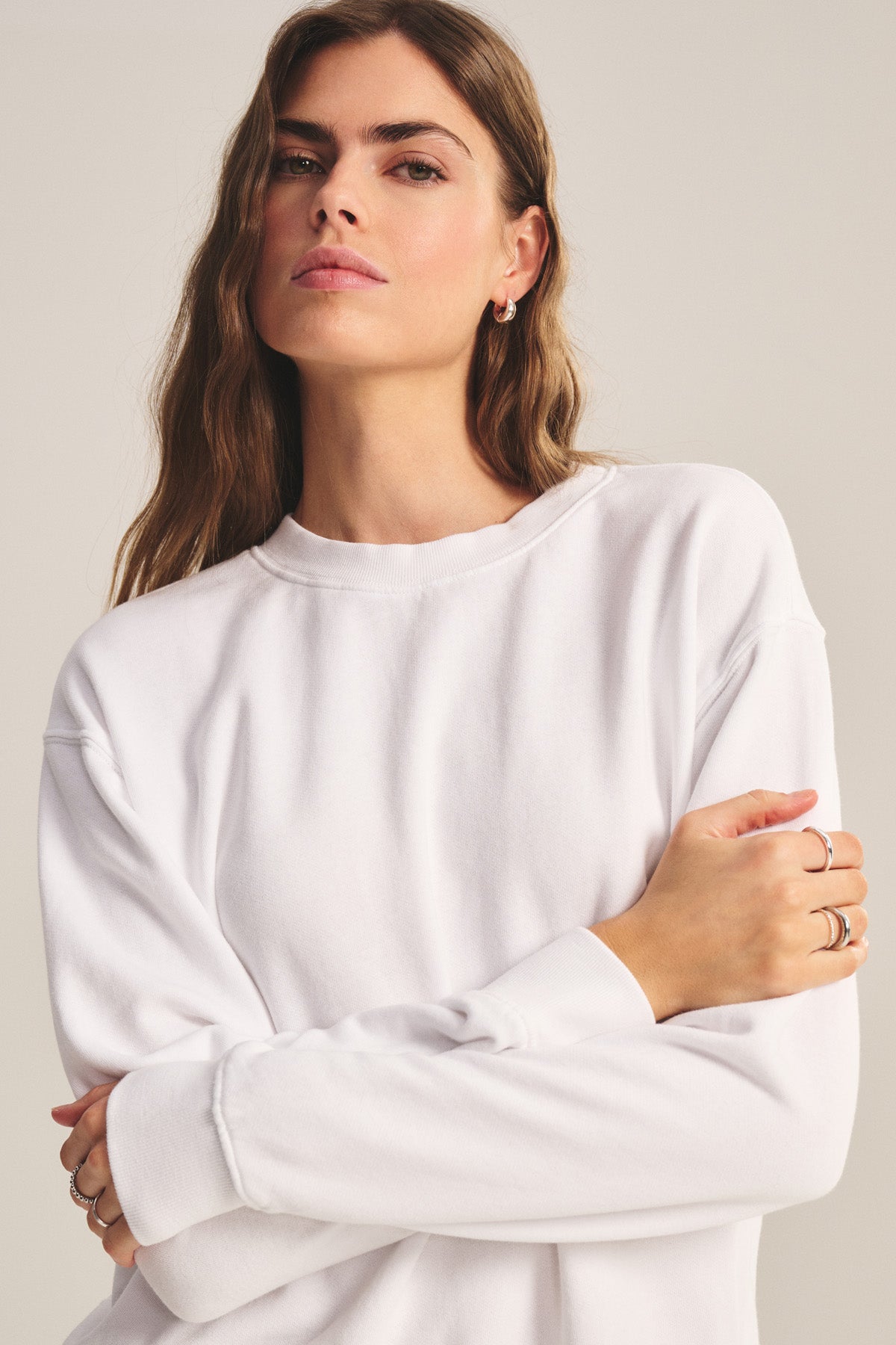 Woman with long brown hair wears the YOKO SWEATSHIRT by Velvet by Graham & Spencer, standing with arms crossed and looking at the camera in a neutral pose.-40293969494209