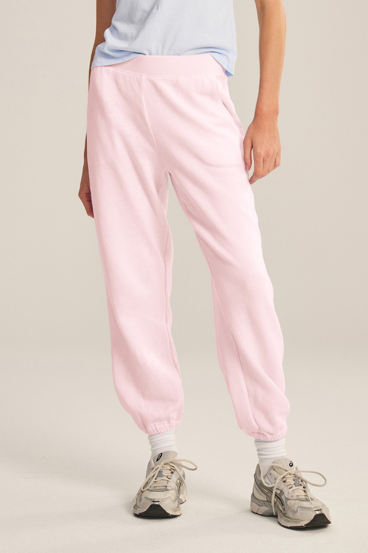 A person stands against a plain background in relaxed fit ZARA SWEATPANT by Velvet by Graham & Spencer, paired with a light blue t-shirt, white socks, and gray sneakers for a comfortable and stylish casual look.