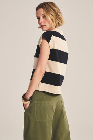 A person wears the ZOELLA SWEATER POLO by Velvet by Graham & Spencer, styled in a cropped fit with wide stripes, paired with olive green patch pocket pants, standing back to the camera and head slightly turned.