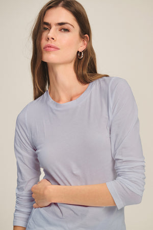 Woman with long brown hair wears the ZOFINA TEE by Velvet by Graham & Spencer—a fitted, ultra-soft gauzy whisper long sleeve crewneck—while looking at the camera with a neutral expression against a plain background.
