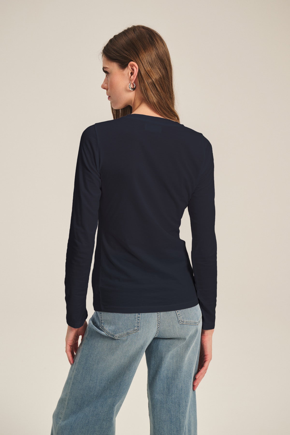 A person with long brown hair, seen from behind against a neutral background, wears the ZOFINA TEE by Velvet by Graham & Spencer in navy paired with light blue jeans.