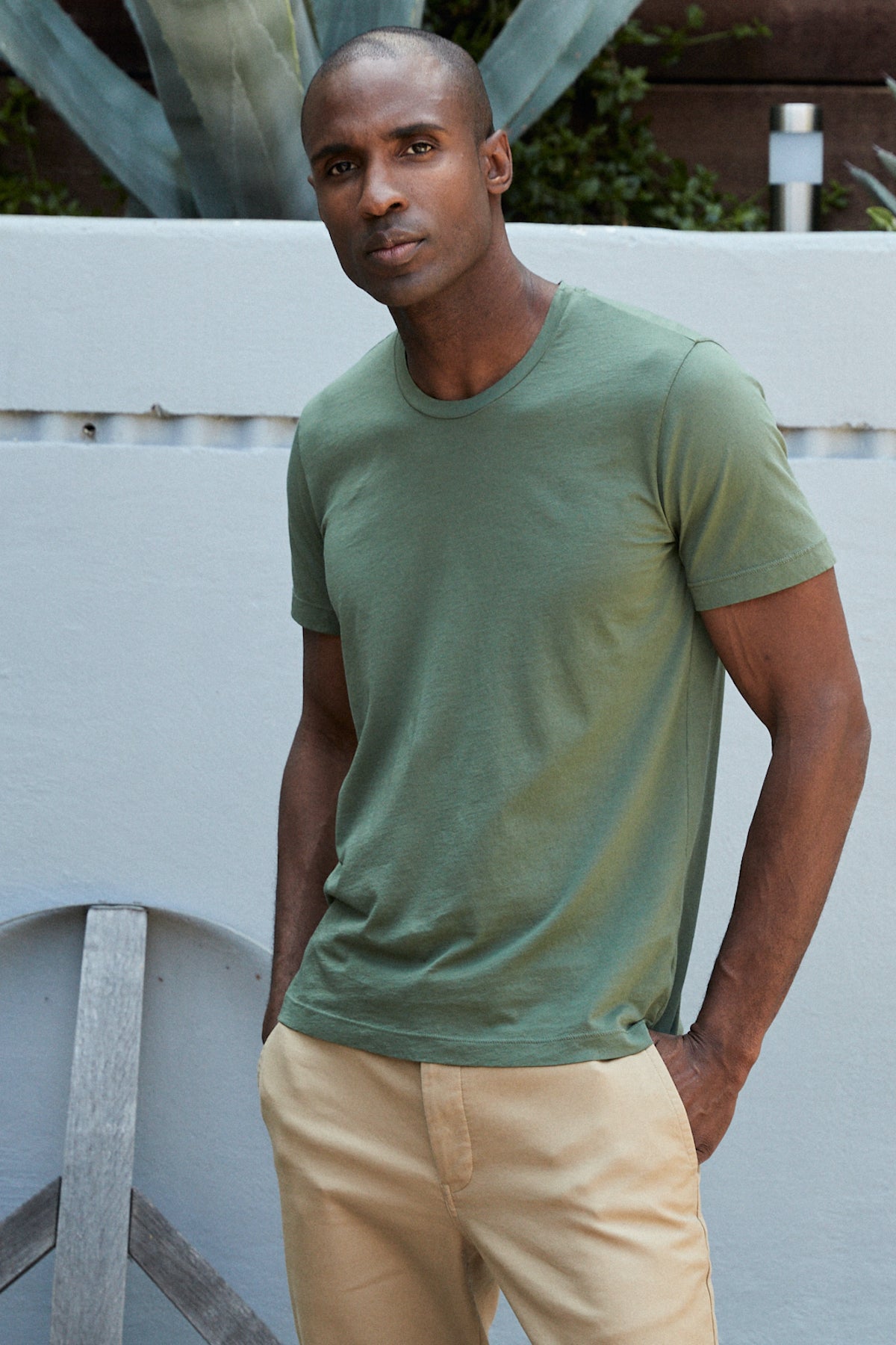  A man wearing a Velvet by Graham & Spencer HOWARD WHISPER CLASSIC CREW NECK TEE in green and khaki pants. 