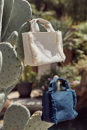 Mini Launch canvas totes in natural and navy hanging on cactus.