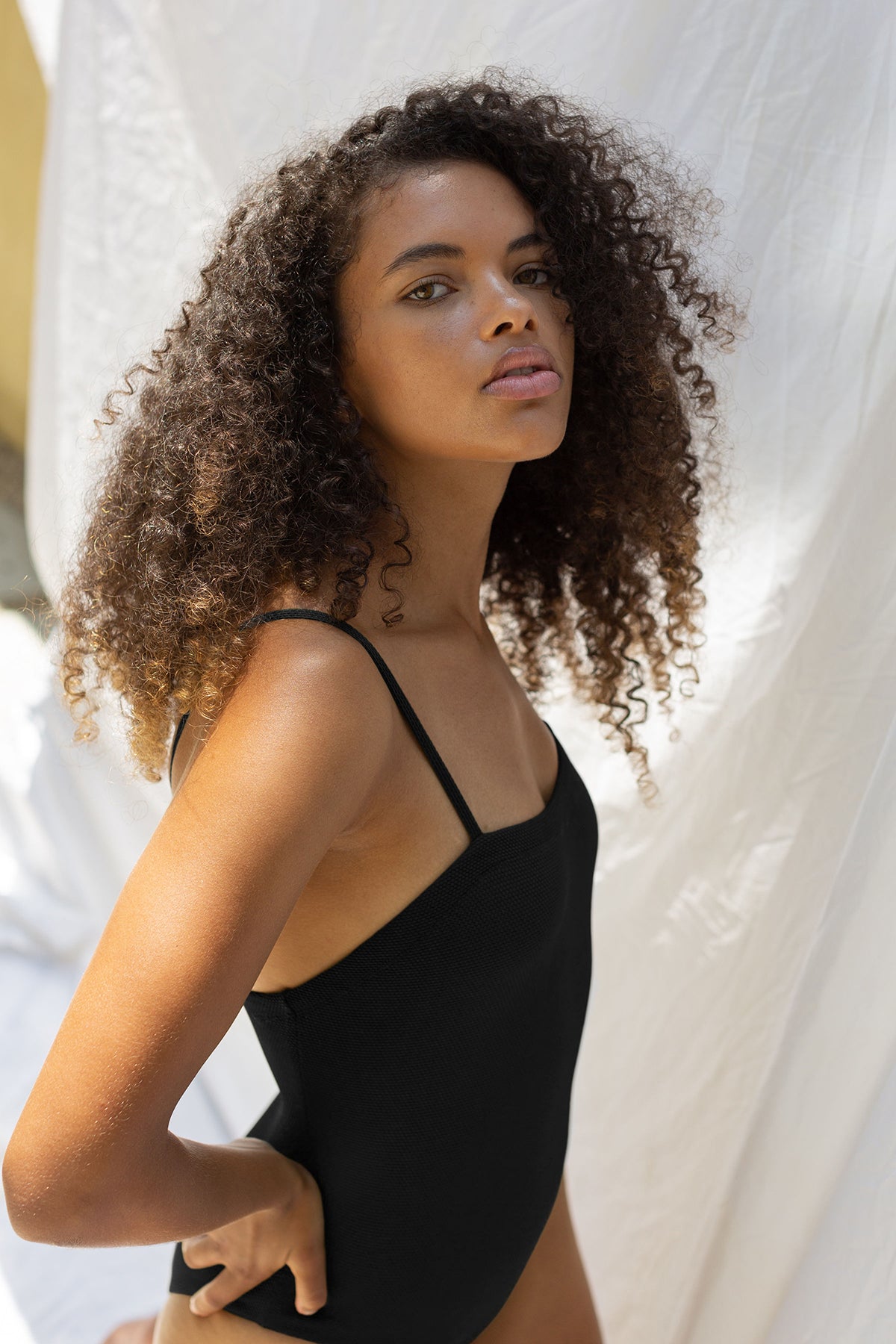   A woman in a black Slow Motion Textured One Piece swimsuit by Laya posing for a photo. 