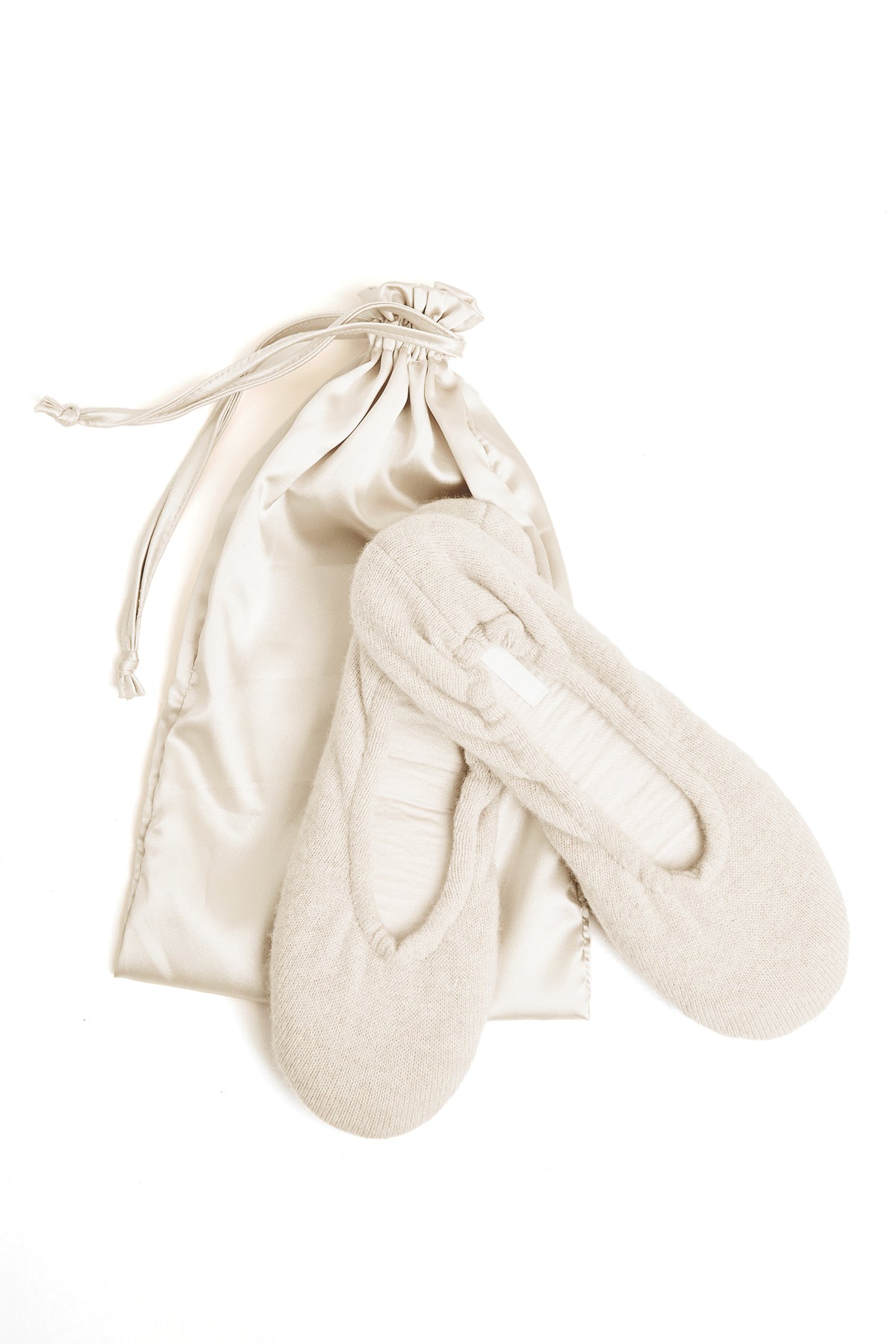 A pair of Skin cashmere ballet flat slippers and a bag on a timeless white surface.-15274767548609