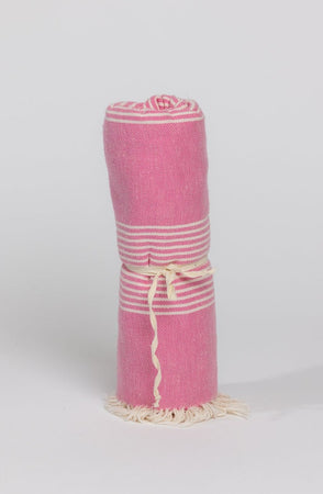 a pink Velvet by Graham & Spencer BEACH THROW with fringes and tassels.