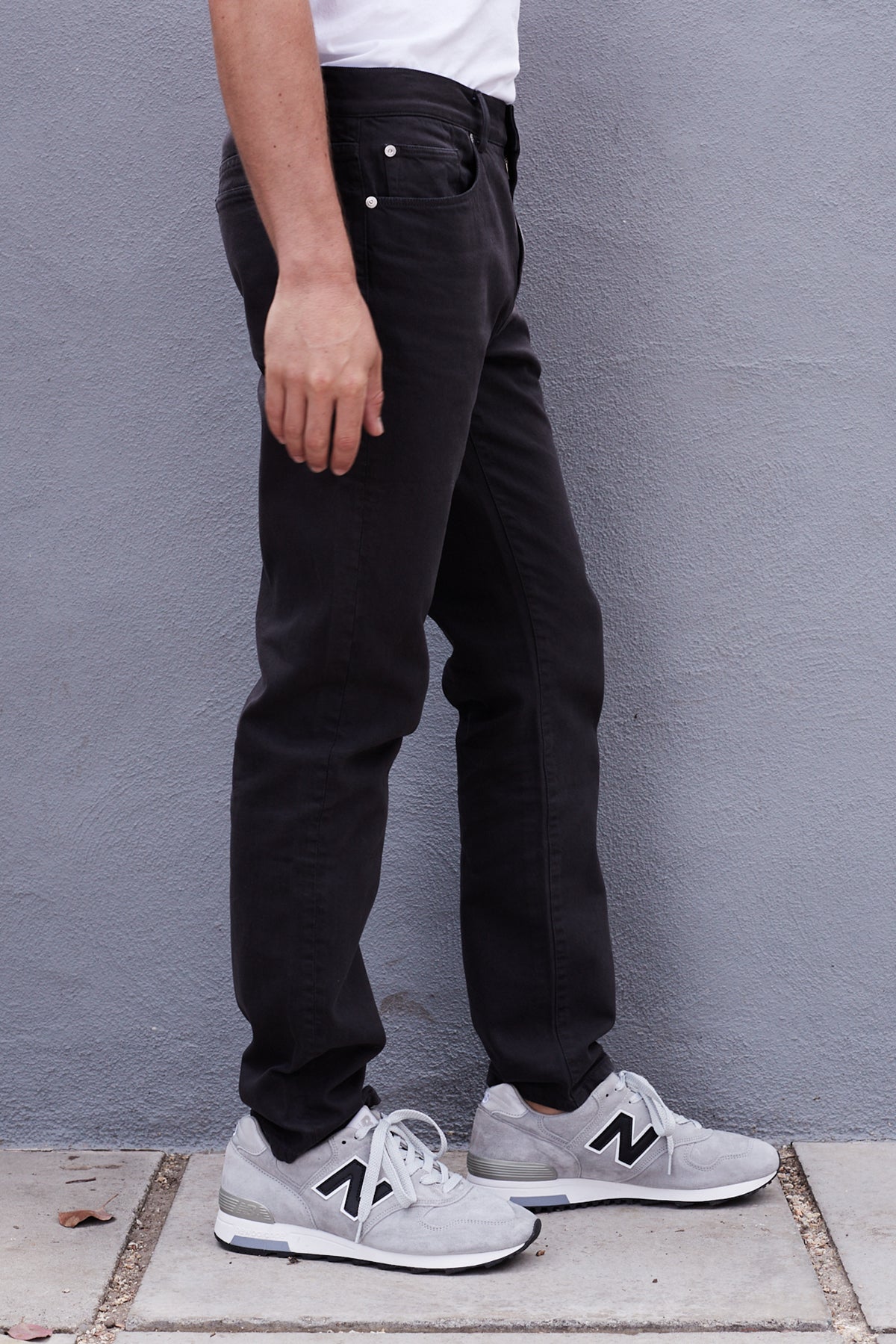 a man wearing Joseph Cotton Canvas Pant by Velvet by Graham & Spencer and sneakers standing next to a gray wall.-25083081588929