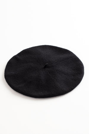 A black Gigi Beret by Hansel from Basel, made of a cozy Merino wool blend, resting on a clean white surface.