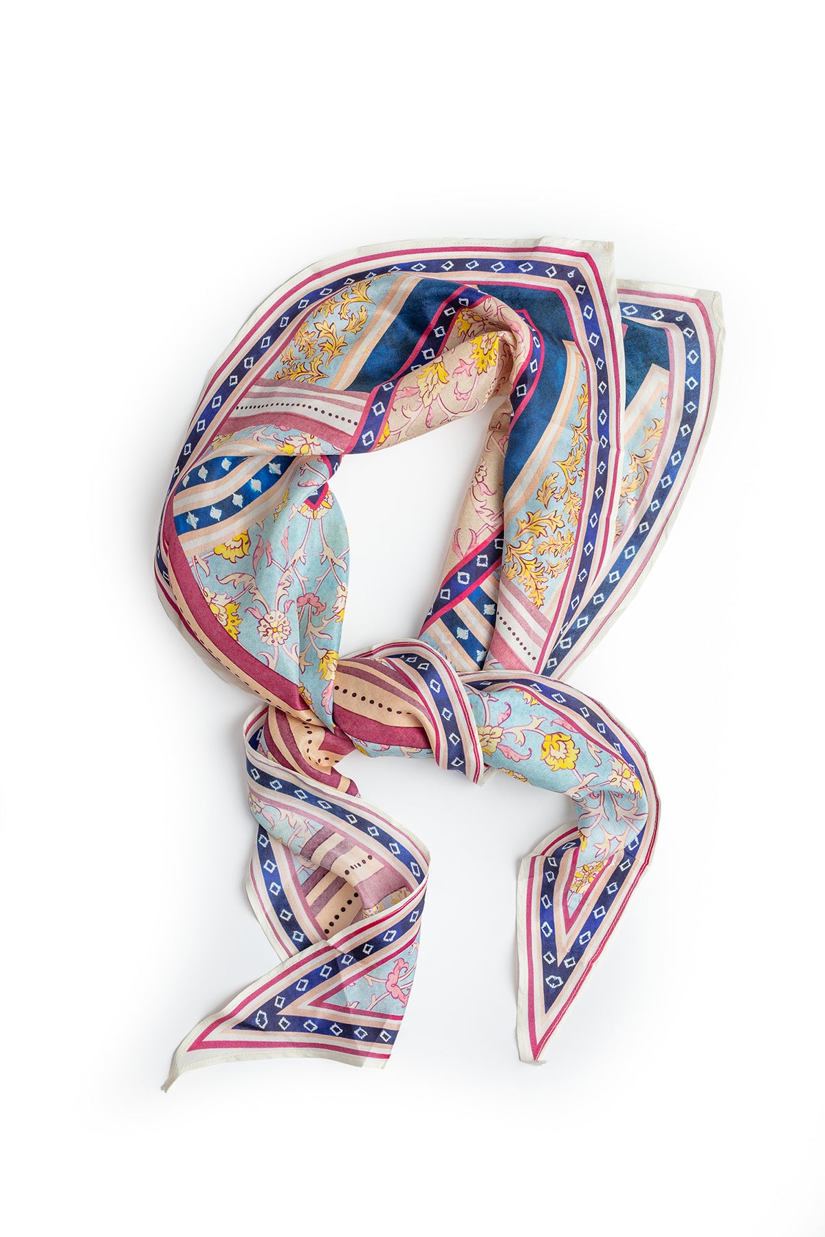   The DIAMOND SHAPE SILK SCARF by Velvet by Graham & Spencer features a colorful, intricate pattern with shades of blue, pink, and white, arranged in a loose loop on a white background—perfect to style as a chic bandana. 