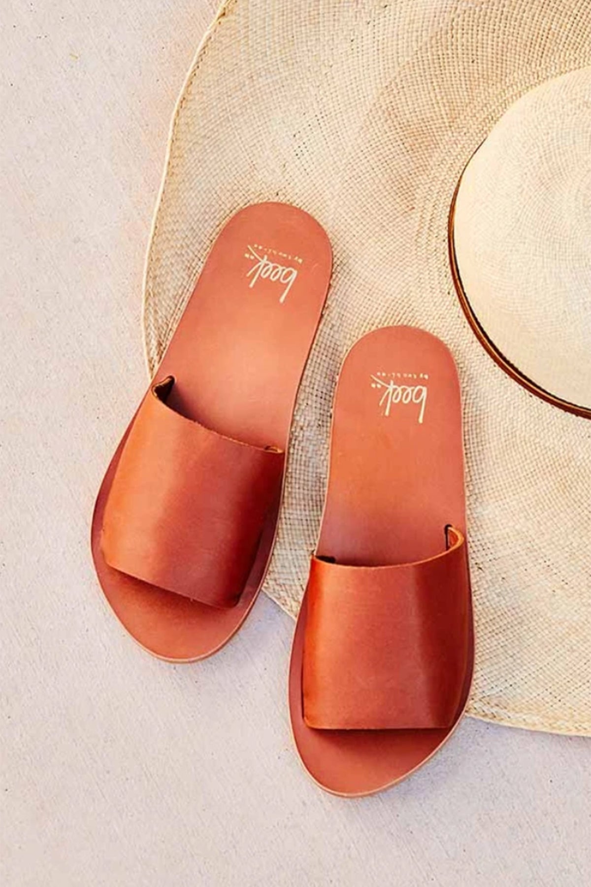   a pair of brown Mockingbird sandals by Beek with a straw hat. 