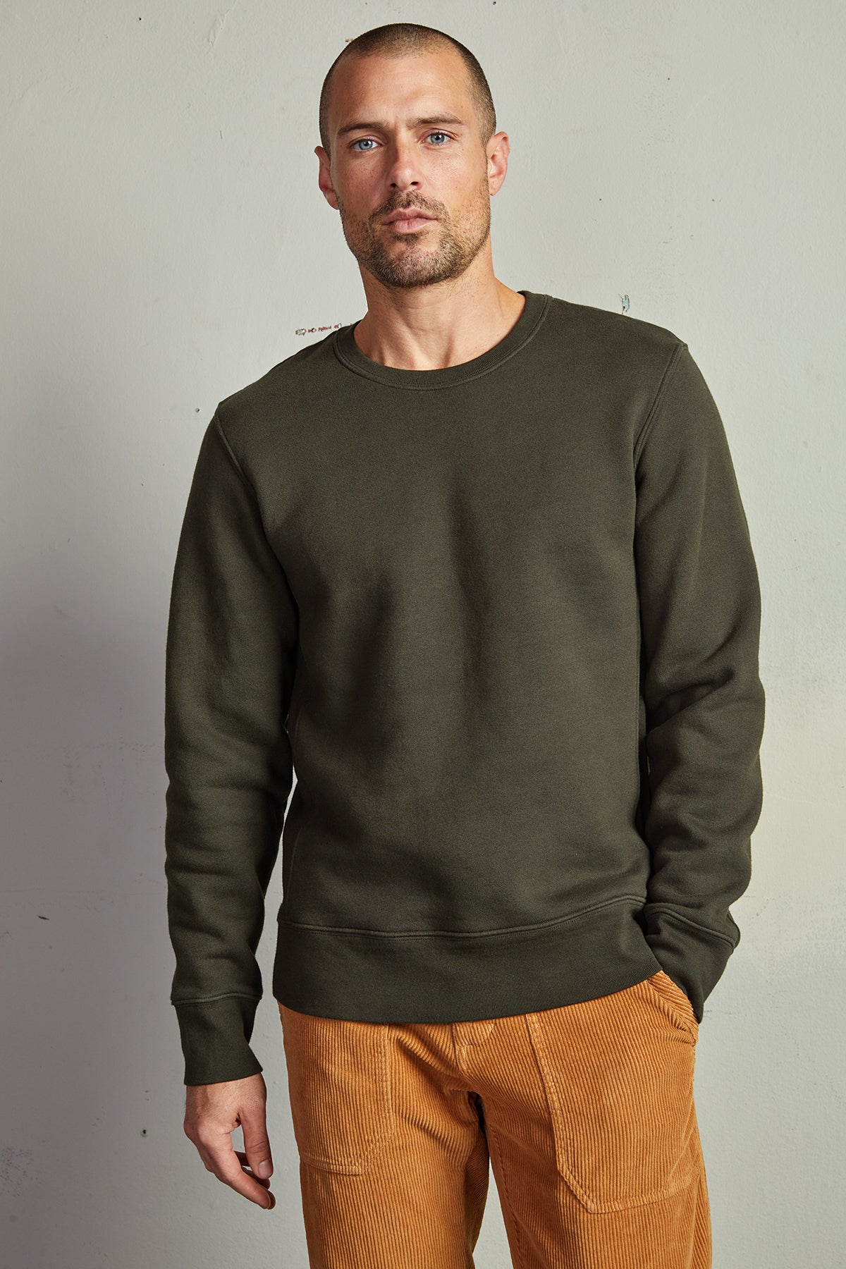 A man wearing a Velvet by Graham & Spencer KING CREW NECK SWEATSHIRT and brown pants with clean lines.-14904712724673