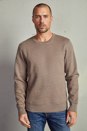 A man wearing a Velvet by Graham & Spencer KING CREW NECK SWEATSHIRT and jeans with clean lines.