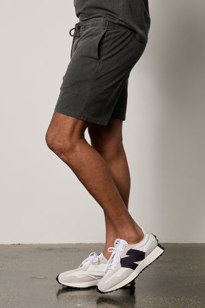 a man wearing Velvet by Graham & Spencer BERT DRAWSTRING SHORT shorts and sneakers.
