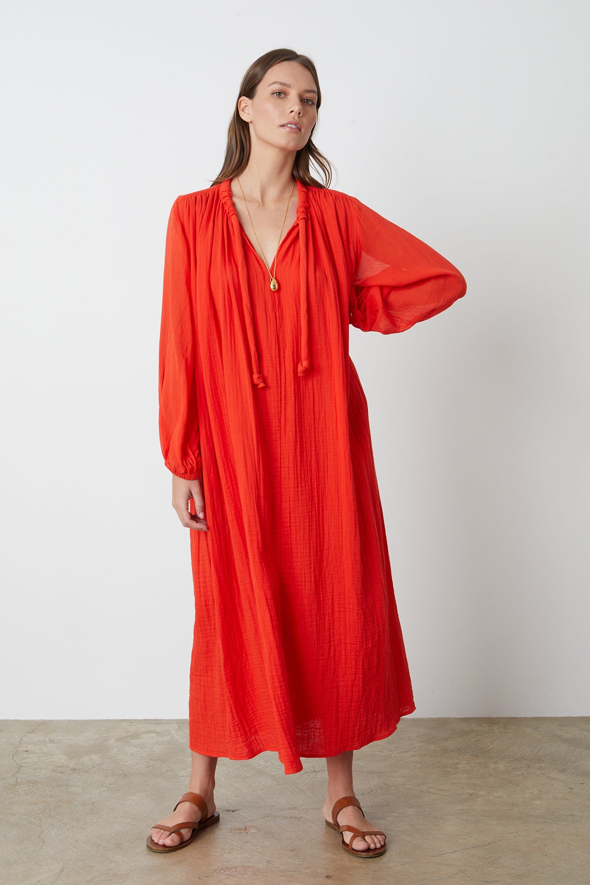Carmella Maxi Dress in bright red cardinal color gauze model with one hand on hip facing front with gold necklace full length front-26255708324033