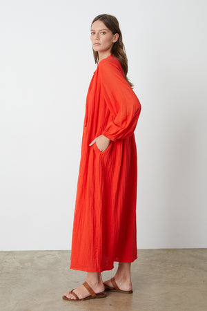Carmella Maxi Dress in bright red cardinal color gauze model standing to the side with hand in pocket