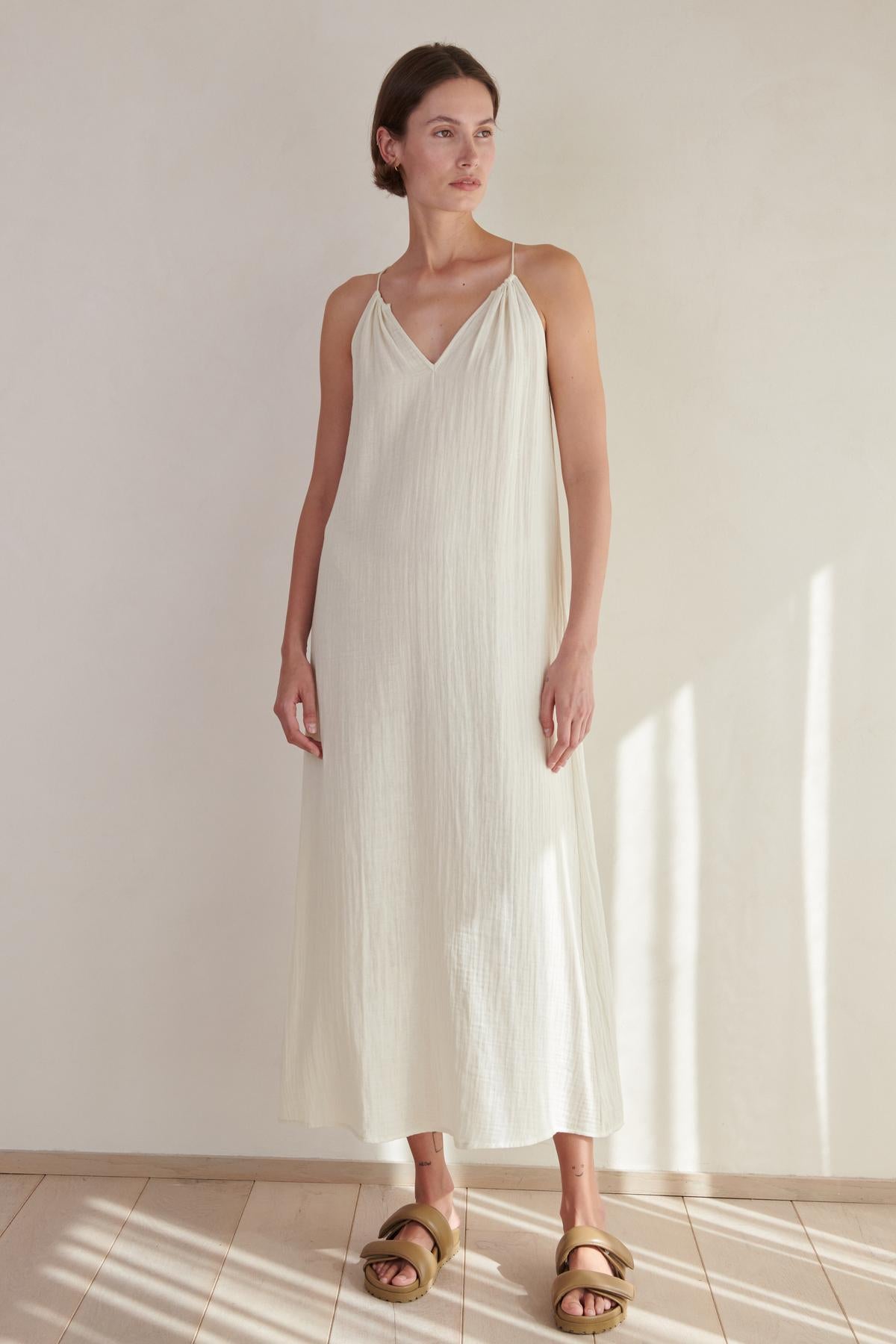 a woman wearing a white velvet by Jenny Graham Carrillo dress and sandals.-26293219754177