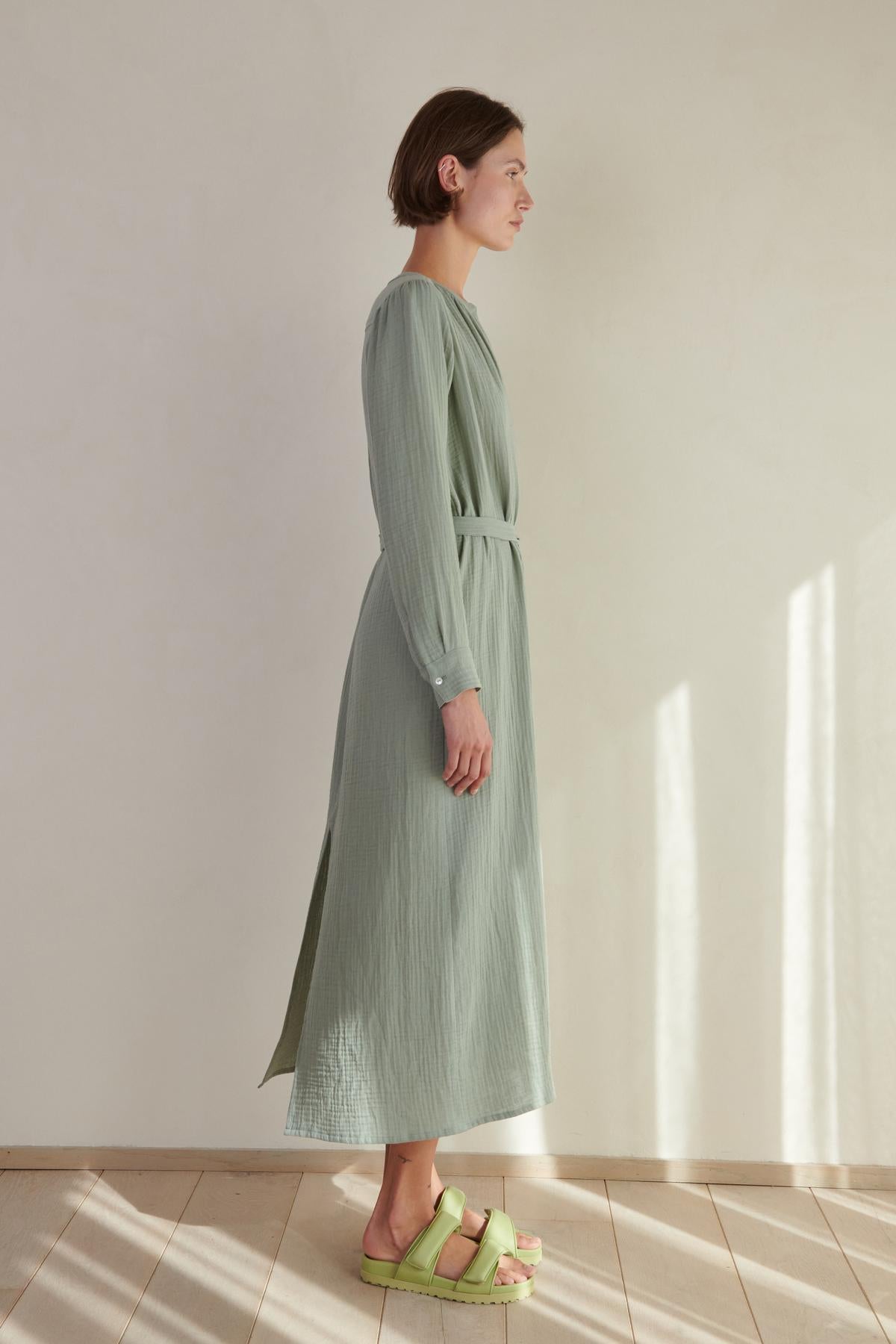   A woman wearing a Velvet by Jenny Graham DOHENY DRESS and green sandals. 