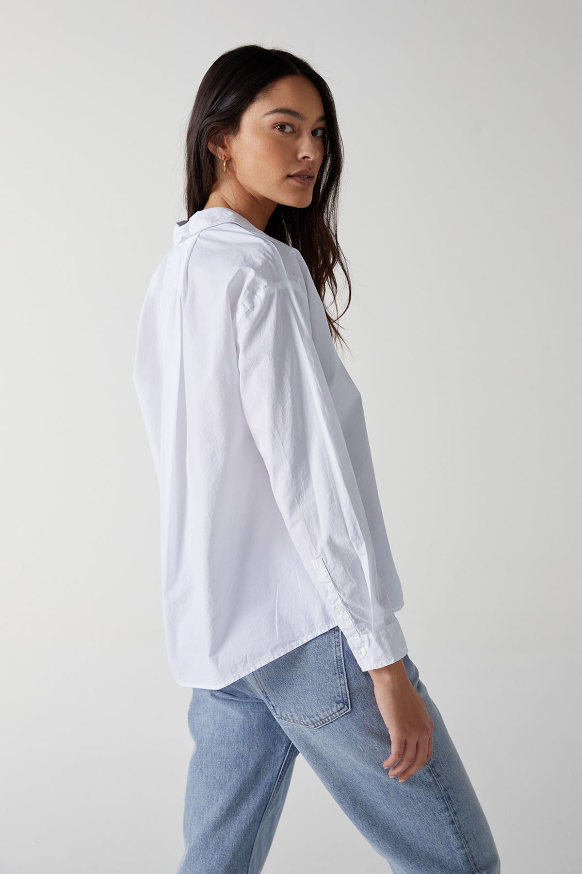 Velvet by Jenny Graham Brea Cotton Shirt in White with Blue Denim and Gold Hoop Earrings, Model Standing to Show Side, Sleeve and Back.-25154669969601