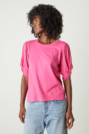 a woman wearing a pink AMELIA PUFF SLEEVE TEE by Velvet by Graham & Spencer and jeans.