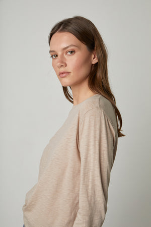The model is wearing a Beige HESTER CREW NECK TEE by Velvet by Graham & Spencer and jeans.