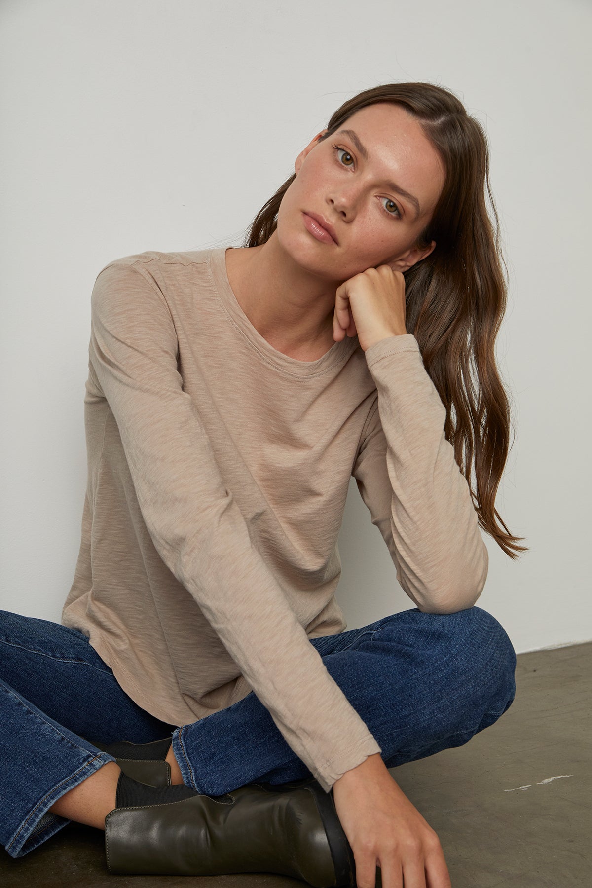   a woman sitting on the floor wearing jeans and a beige long - sleeved HESTER CREW NECK TEE by Velvet by Graham & Spencer. 
