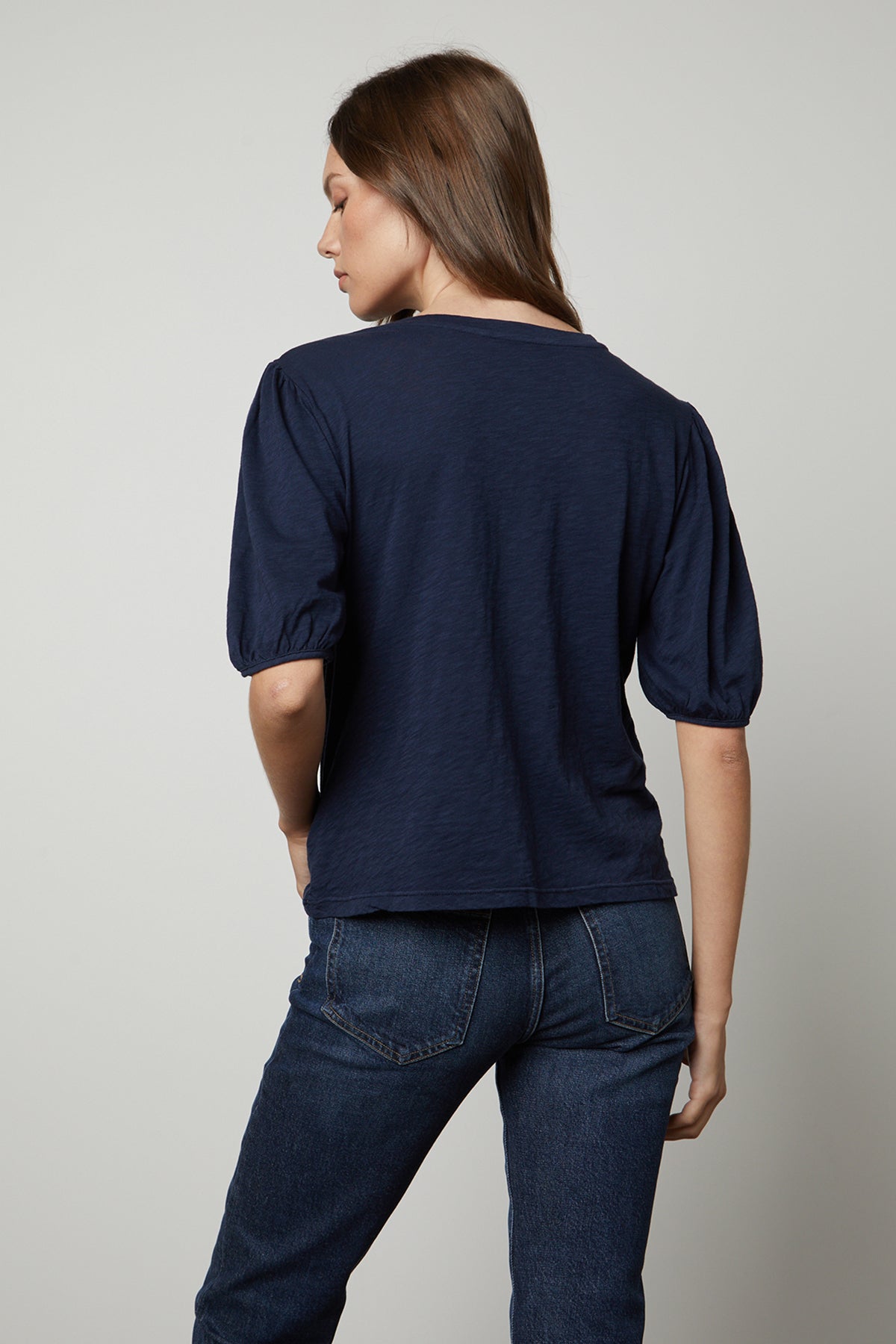 the back view of a woman wearing jeans and a Velvet by Graham & Spencer JOELLA PUFF SLEEVE TEE.-25954591506625