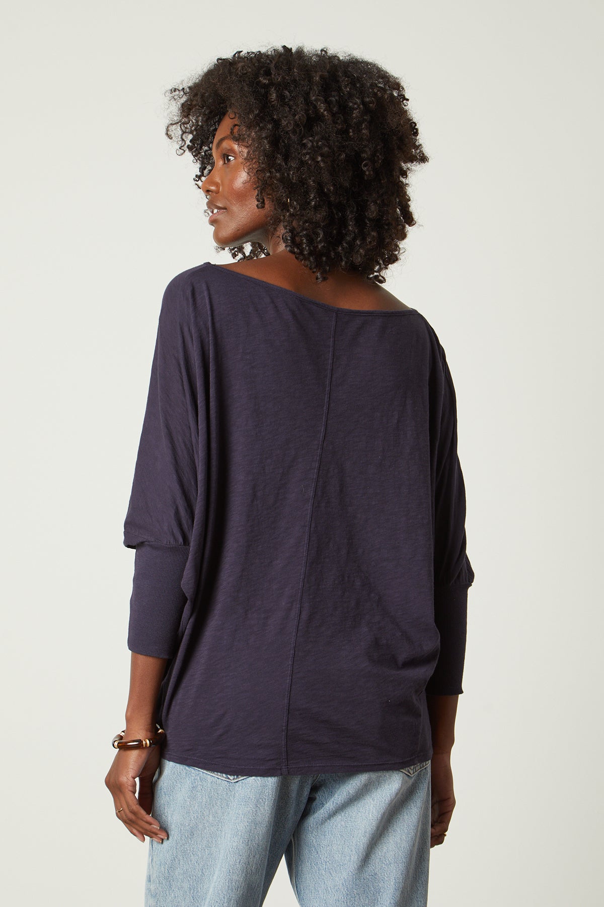  the back view of a woman wearing JOSS DOLMAN SLEEVE TEE by Velvet by Graham & Spencer jeans and a long-sleeved top. 