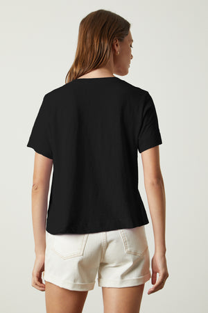 the back view of a woman wearing a Velvet by Graham & Spencer LULA COTTON SLUB SWING TEE and white shorts.