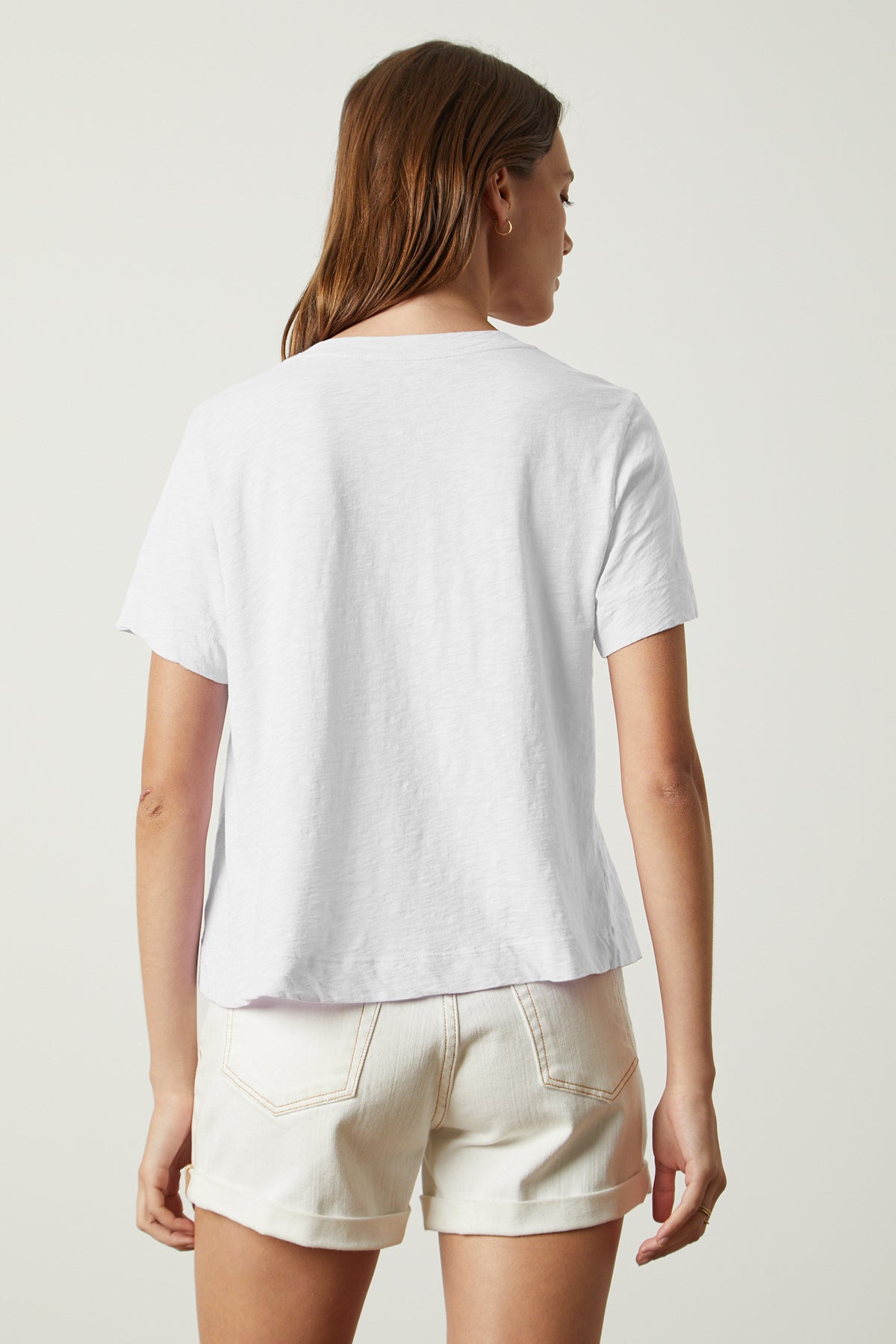 The back view of a woman wearing white shorts and a Velvet by Graham & Spencer LULA COTTON SLUB SWING TEE.-26235777941697
