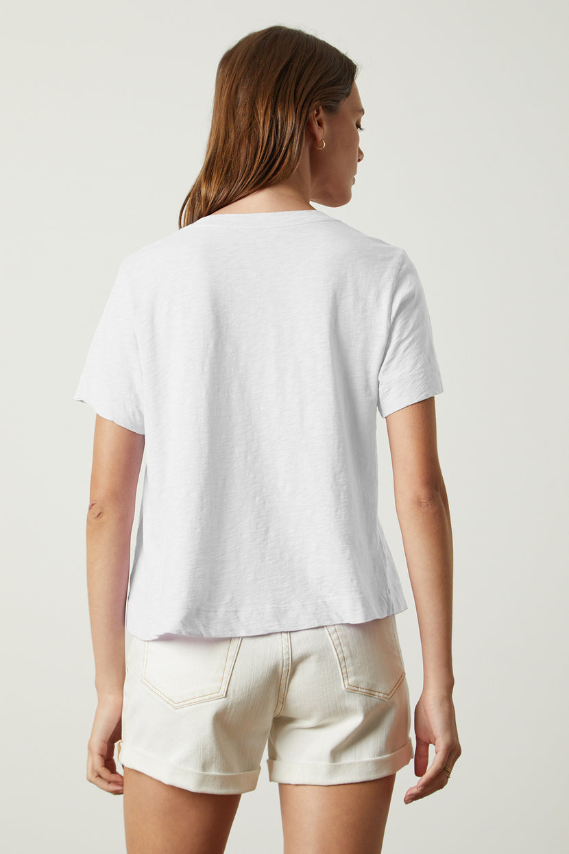 The back view of a woman wearing white shorts and a Velvet by Graham & Spencer LULA COTTON SLUB SWING TEE.