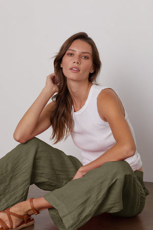 Model sitting on floor wearing Lola linen pant in olive green with Maxie tank in white 