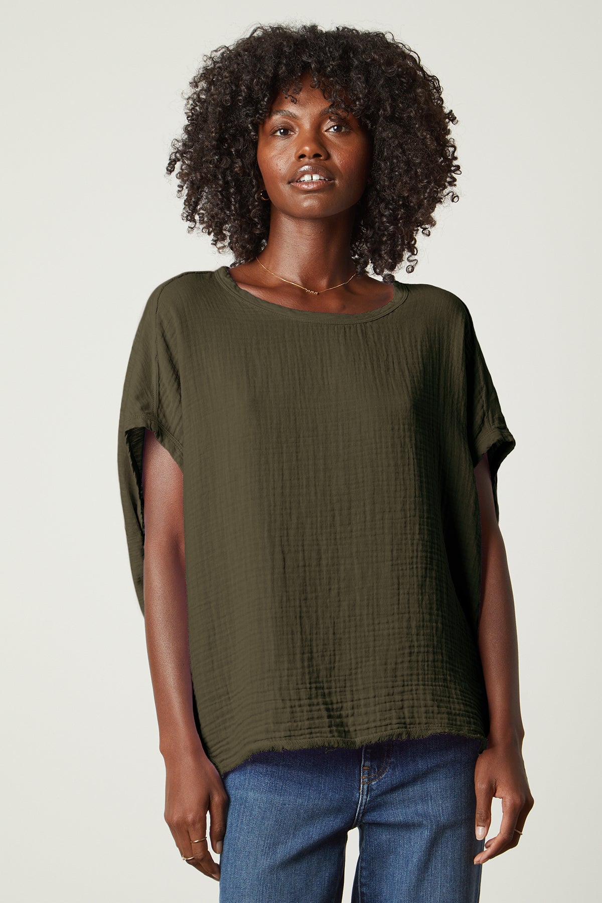   a woman wearing a green Velvet by Graham & Spencer CORA BOXY TEE top and jeans. 