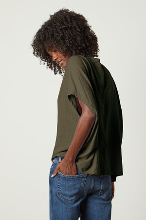 the back view of a woman wearing CORA BOXY TEE jeans and a green top by Velvet by Graham & Spencer.