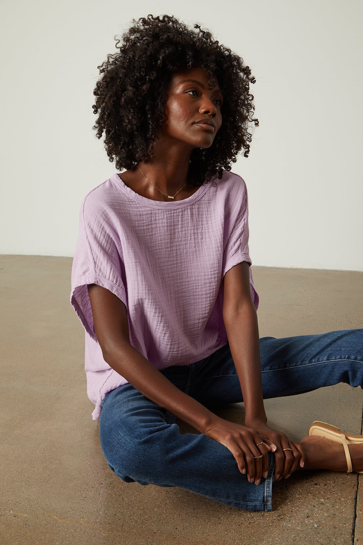   A woman is sitting on the floor in a Velvet by Graham & Spencer CORA BOXY TEE. 
