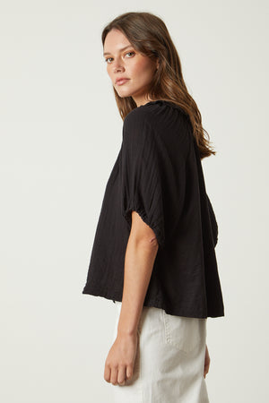 The back view of a woman wearing a Velvet by Graham & Spencer Ilene Puff Sleeve Top with a V-neckline.
